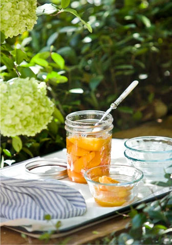 A jar of peaches on a tray outdoors