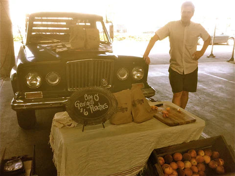 Old image of a man standing next to an old truck